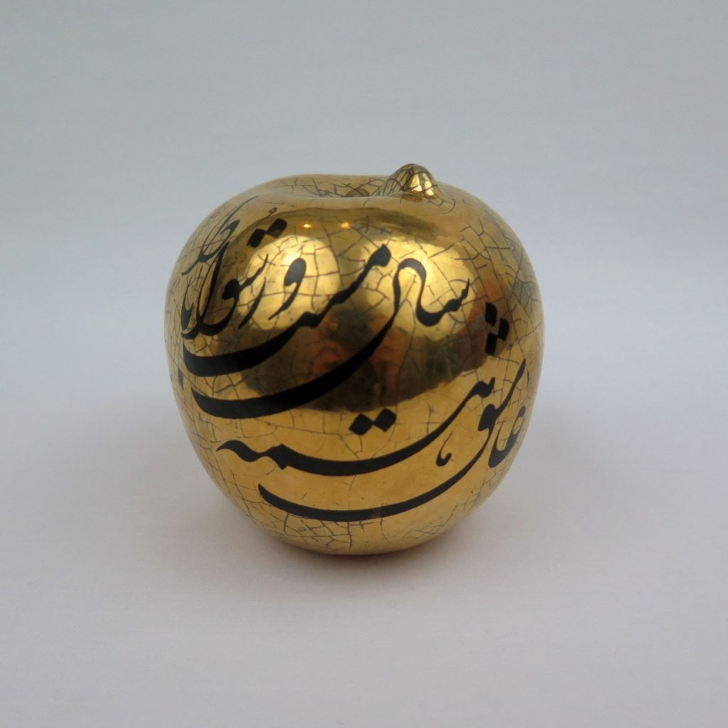 big golden apple with Persian calligraphy design viewed from front side