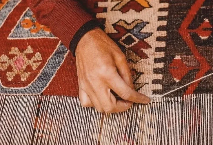 Close-up of a hand-woven Persian carpet showcasing intricate craftsmanship and detailed patterns.