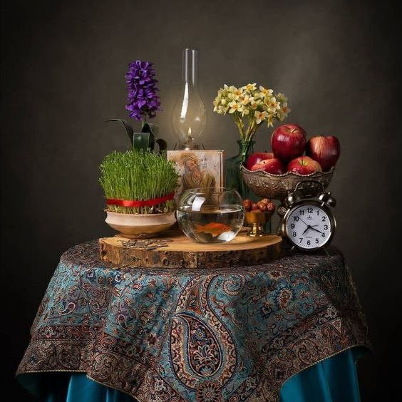 Traditional Haft Sin table for Nowruz with symbolic items, a mirror, candles, goldfish, and flowers.