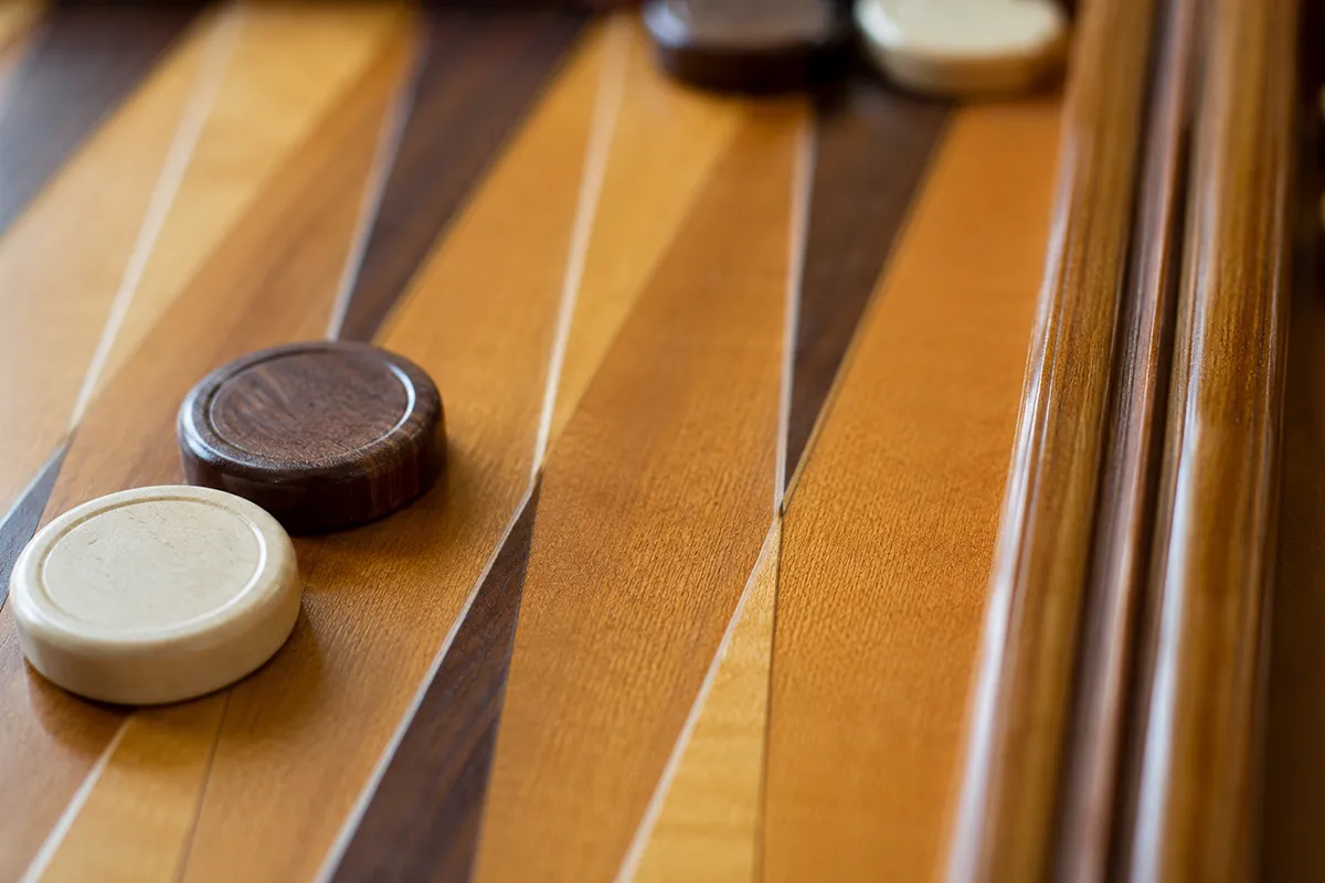 Close-up of a wooden backgammon board showing the triangular points and the central bar