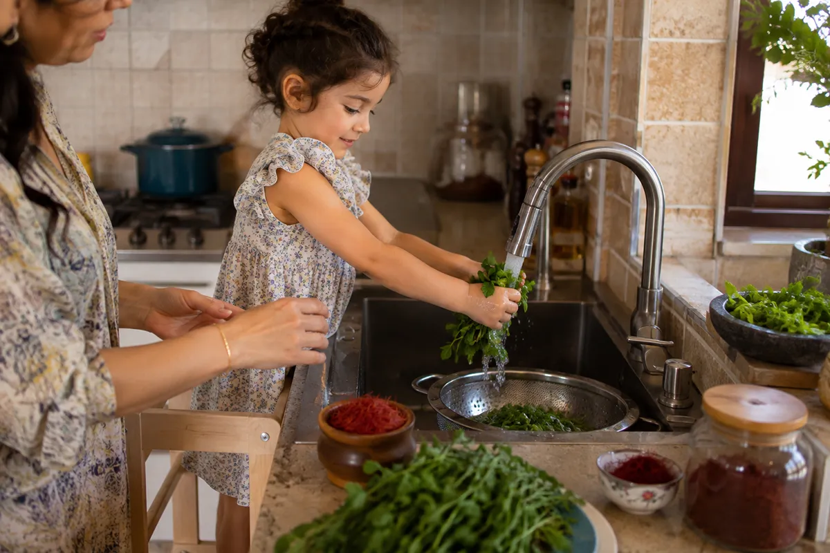 A young child helping prepare Persian food in the kitchen